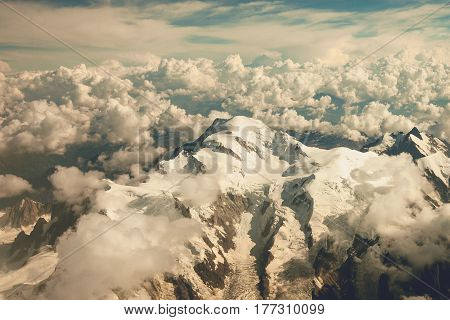 View of the snow-covered Alps and clouds from the window of the plane