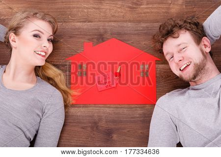 Housing marriage family security future finances mortgage concept. Just married lying on floor. Young man and woman next to home symbol with keyring.
