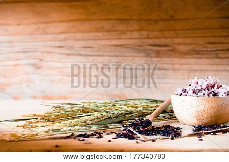 The Brown Rice In Bowl With Ear Of Pappy Rice On Wooden Table