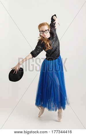 Sweet hipster ballerina in a tutu pointe shoes and sunglasses dancing with a hat. Modern dance. Youth culture