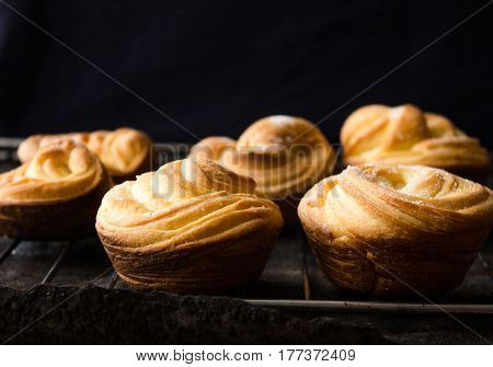 Cruffin - Buns from yeast dough. Dark graunge background. Mystical light. cinnamon craffin (cinnabon) (mix of croissant and muffin)