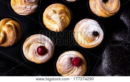 Cruffin - Buns from yeast dough. Dark graunge background. Mystical light. cinnamon craffin (cinnabon) (mix of croissant and muffin)
