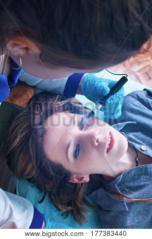 The ophthalmologist doctor performs an operation to diagnose the eyeball, eyesight of a young girl. Virtual laser for checking vision.