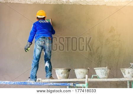 Construction worker using trowel plastering concrete during wall covering works with self-levelling cement mortar
