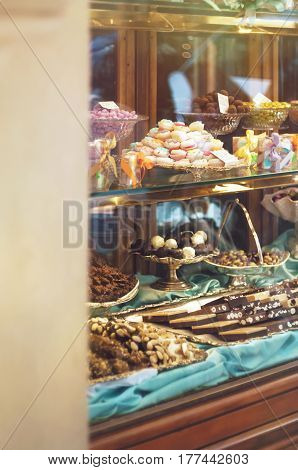 Rich variety of chocolates and candies in display window of italian pastry shop in the street of Florence at sunny day