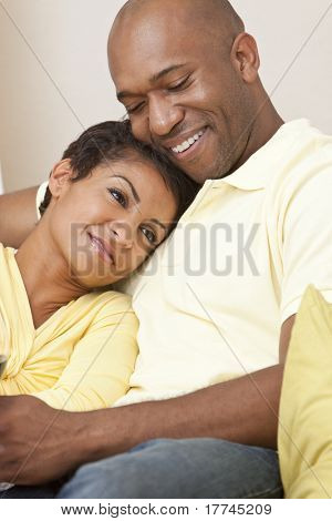 幸せなアフリカ系アメリカ人男性と女性カップル一緒に笑みを浮かべて自宅で座っている 30 代で。