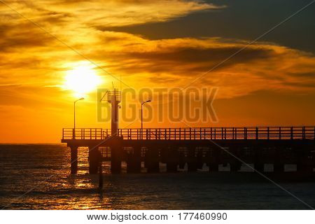 Sunny sunset through the pier going into the sea