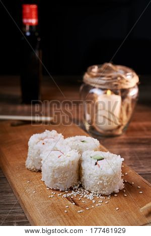 Japanese food sushi roll with crab sesame seeds cucumber cheese on a wooden board svea in the background