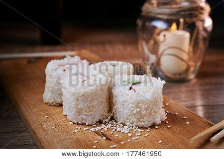 Japanese food sushi roll with crab sesame seeds cucumber cheese on a wooden board svea in the background