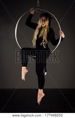 Attractive aerialist woman exercising on aerial ring (lyra)