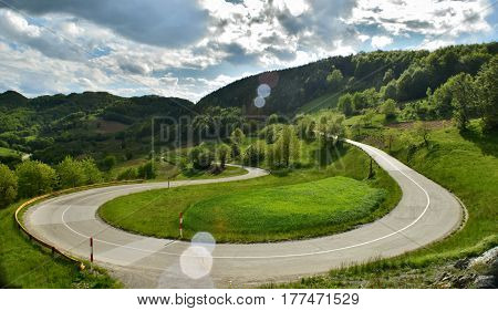 circular bend in the road in the mountains with green trees as a landscape