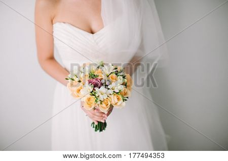 Bride in a white wedding dress holding a bouquet from spring flowers in hands on a white background. marriage concept. gatherings of bride.