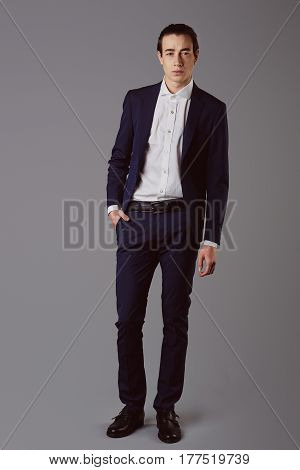 Business fashion man wearing blue suit with white shirt. Studio shot against grey. Processed with VSCO s3 preset
