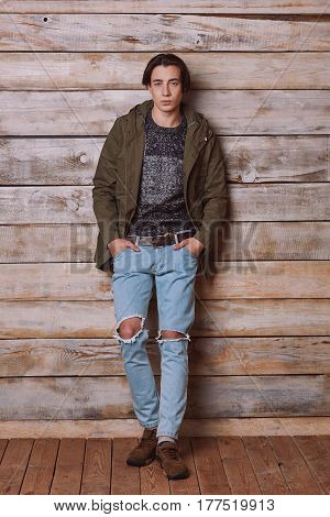 Handsome man wearing green jaket and torn jeans in wooden rural house interior. Processed with VSCO k2 preset