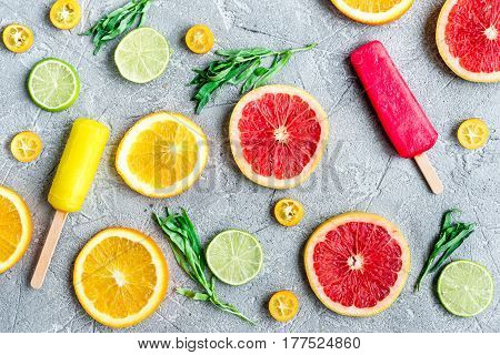 homemade citrus popsicles with fresh fruit slices on stone table background top view pattern