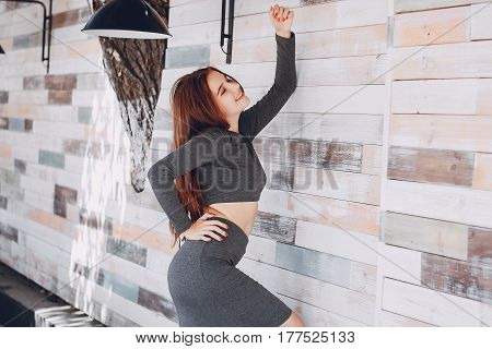 girl stands near the wall in a grat skirt