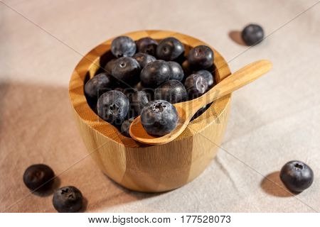 big blueberry in small wooden bowl on textile background