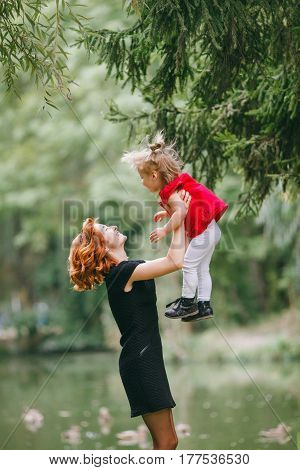 mom and little daughter walking in green summer park