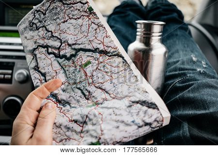 Closeup Woman Hands With Map And Feet In Cute Socks And Jeans On Car Dashboard. Drinking Water On Ro