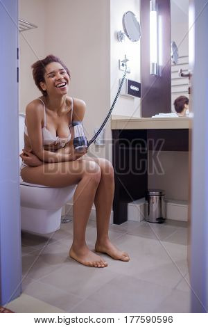 Young Woman Blow Drying Hair In Bathroom