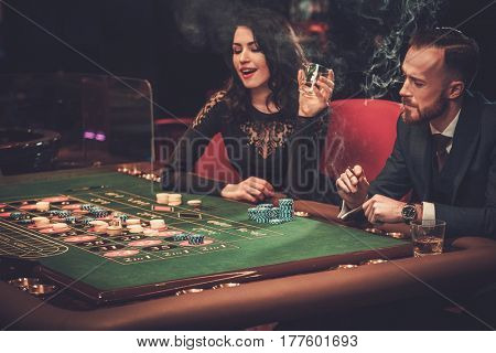 Upper class friends gambling in a casino.