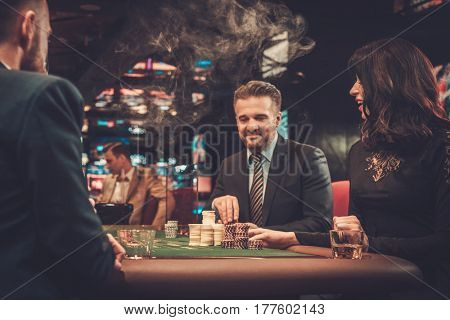 Upper class friends gambling in a casino.