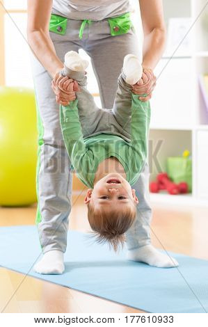 woman and cute kid son doing yoga exercises at mat