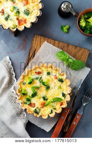 Homemade quiche tart with red fish salmon broccoli basil seasonings and cheese on a gray stone background. Selective focus.Top view.