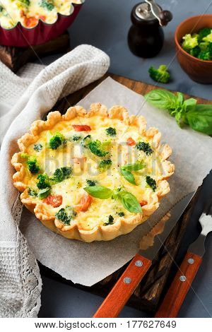 Homemade quiche tart with red fish salmon broccoli basil seasonings and cheese on a gray stone background. Selective focus.