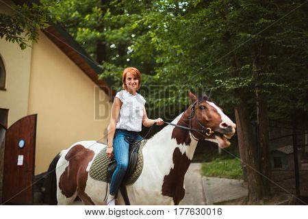 Portrait of happy young woman riding on a beautiful horse