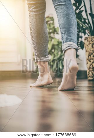 Floor heating. Young woman walking in the house on the warm floor. Gently walked the wooden panels.