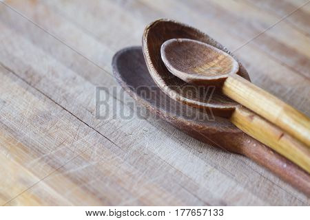 side view of hand crafted wooden kitchen spoons in many sizes and shapes on a wood cutting board selective focus copyspace