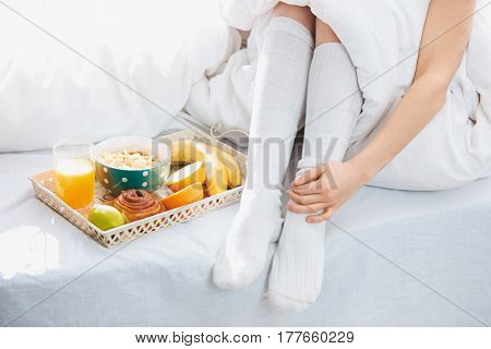 Partial view of male and female legs and breakfast on bad tray