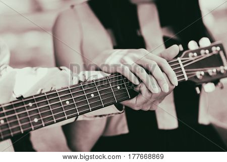 The guy learns to play guitar with his girlfriend. Couple. Male and female hand close up.