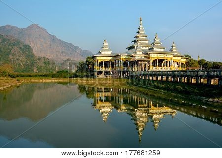 Kyaut Ka Lat Buddhist Temple reflecting in the water of the lake at sunset. Hpa-An Myanmar.