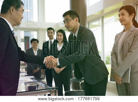 Business people greeting by handshake and take a bow