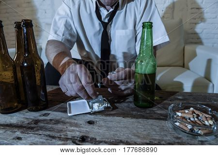 wasted alcoholic and drug addict man with loose tie snorting cocaine and drinking beer bottles at home living room couch in toxic substance addiction and abuse concept