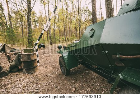 Russian Armoured Soviet Scout Car Ba-64 Of World War II Near German Checkpoint With Open Barrier On Forest Road. Vehicle Of Red Army. Killed German Soldiers On ground.