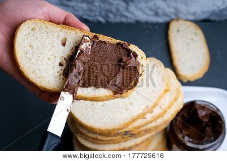 Sweet chocolate cream in jar on table. Nutella with buttered bread