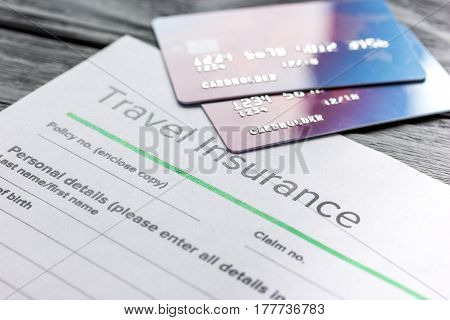 Travel insurance application form with credit cards on gray wooden desk background
