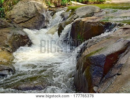 Small waterfalls, streams and rocks part from big river.