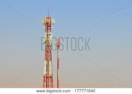 Antenna repeater tower for mobile phones with a blue sky. Antenna for mobile signal near city.