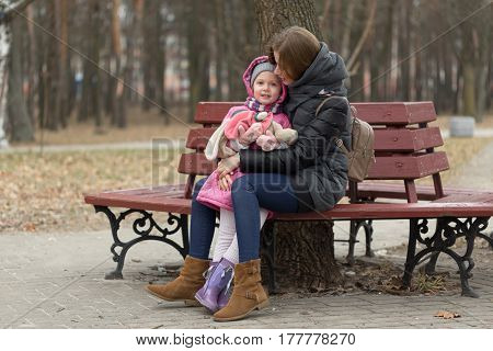 Mom And Daughter Are Sitting On A Park Bench