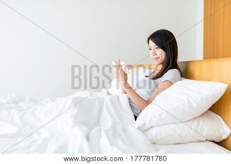 Woman watcing on mobile phone and lying on bed
