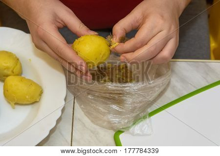 Close-up of hands peeling potato before cooking