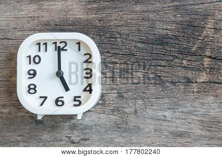 Closeup white clock for decorate in 5 o'clock on old wood floor textured background with copy space