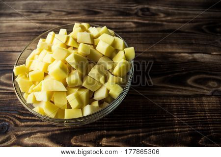 a bowl with cutted fresh potato wooden background