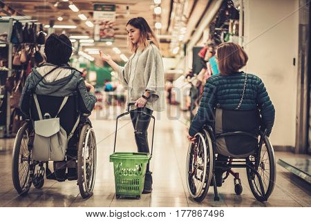 Young girl helping two disabled women in wheel chair in a department store