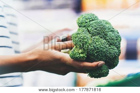 The buyer weighs the green fresh broccoli close up woman shopping healthy food in supermarket blur background female hands buy nature products in store grocery
