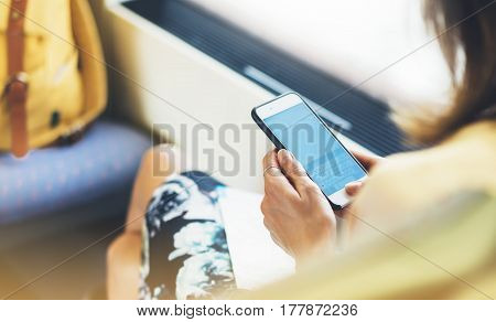 Enjoying travel. Young pretty woman traveling by train sitting near window using smart phone and looking map. Tourist text message and plan route of railway railroad transport concept mock up